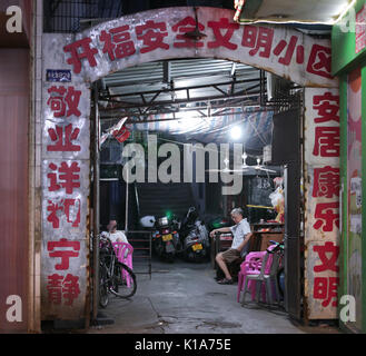 Ältere mans Unternehmen jedes anderen innerhalb eines Korridors befindet in der Stadt Chaozhou, Guangdong, China. Stockfoto