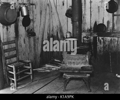 Eine leichte Küche, die zu einem teilpächter, mit einem Holzofen, einem Stuhl warten auf Reparaturen gegen die Wand, und Pfannen und Kessel an den Wänden, Hale County, Alabama, 1936. Von der New York Public Library. Stockfoto