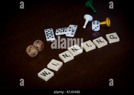 Wort Fliesen, buchstabieren Sie 'gewinnen', verschiedene Brettspiele Utensilien ist in der Nähe. Stockfoto