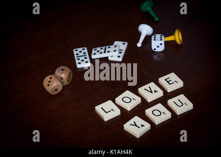 Wort Fliesen, buchstabieren Sie 'Liebe', verschiedene Brettspiele Utensilien ist in der Nähe. Stockfoto
