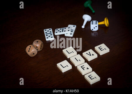 Wort Fliesen, buchstabieren Sie 'Leben', verschiedene Brettspiele Utensilien ist in der Nähe. Stockfoto