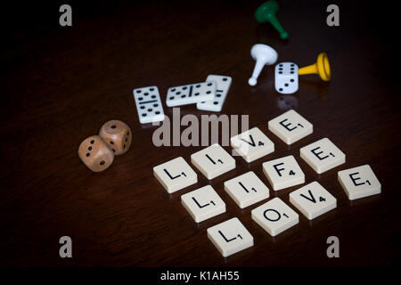 Wort Fliesen spell Out' LEBEN LIEBE', verschiedene Brettspiele Utensilien ist in der Nähe. Stockfoto