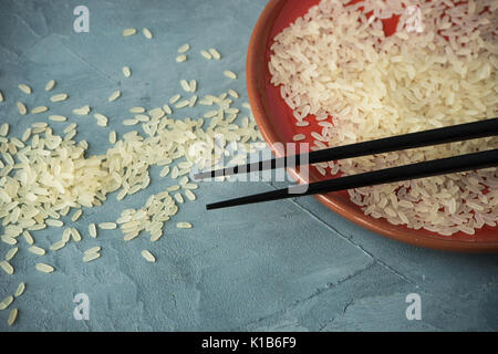 Porzellanteller und Reis auf grauem Beton Tabelle mit Copyspace Stockfoto