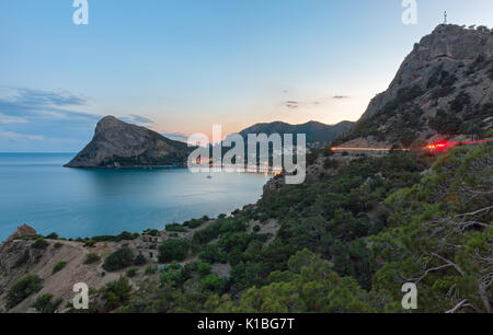 Blick auf die Bucht zum Resort Dorf in der Nähe der Bergen und mit einem großen Landspitze im Meer bei Sonnenuntergang. Das Licht, das durch die serp Trace Stockfoto