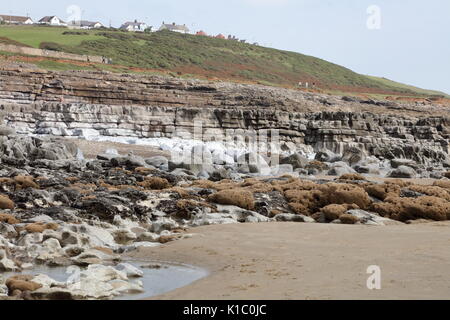 Der Strand seite Klippen mit Wegen und Pfaden auf mit den Häusern von Ogmore vom Meer auf einem schönen typischen Tag. Stockfoto