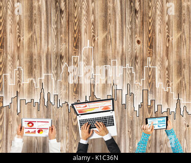 Gruppe von drei Personen mit Geräten in Händen arbeiten zusammen als Symbol der Vernetzung und Kommunikation Stockfoto