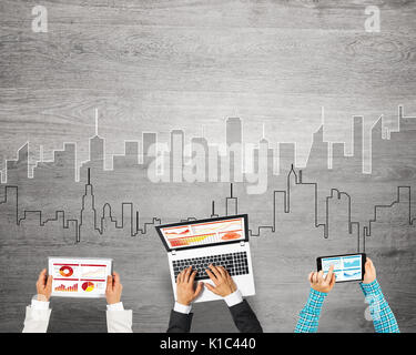 Gruppe von drei Personen mit Geräten in Händen arbeiten zusammen als Symbol der Vernetzung und Kommunikation Stockfoto