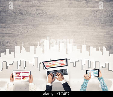 Gruppe von drei Personen mit Geräten in Händen arbeiten zusammen als Symbol der Vernetzung und Kommunikation Stockfoto