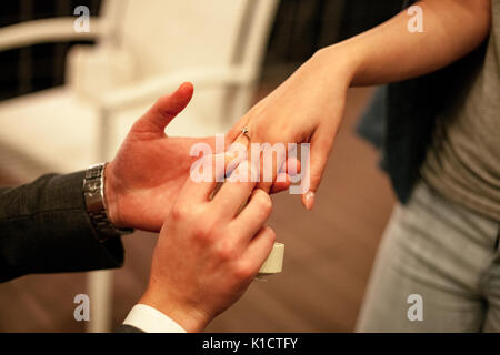 Man macht Frau Heiratsantrag und setzt an Engagement Ring mit Diamant auf den Finger. Close Up. Stockfoto