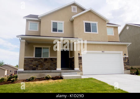 Eine neue schöne Bräune Stuck und Stein Haus mit Gras vor der Tür. Stockfoto