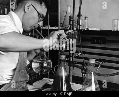 Wissenschaftler arbeiten mit Becher in einem Labor während Schlag in eine Pipette, am Landwirtschaftsministerium der Vereinigten Staaten, Prince Georges County, Maryland, 1935. Von der New York Public Library. Stockfoto