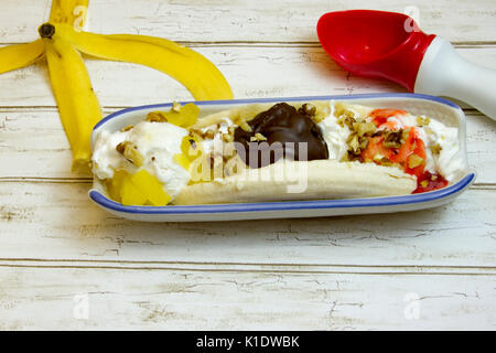 Banana Split mit Schale und Eisportionierer in Boot auf rustikalen, mit Holz. Stockfoto