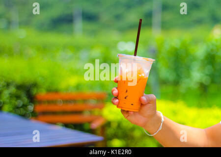 Hand mit Kunststoff Glas Eistee. Stockfoto