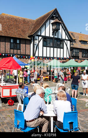 England, Sandwich. Menschen sitzen im Sommer Sonnenschein an Tischen, essen und trinken, in der mittelalterliche Marktplatz mit dem Rathaus aus dem 16. Jahrhundert. Stockfoto