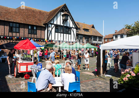 England, Sandwich. Menschen sitzen im Sommer Sonnenschein an Tischen, essen und trinken, in der mittelalterliche Marktplatz mit dem Rathaus aus dem 16. Jahrhundert. Stockfoto