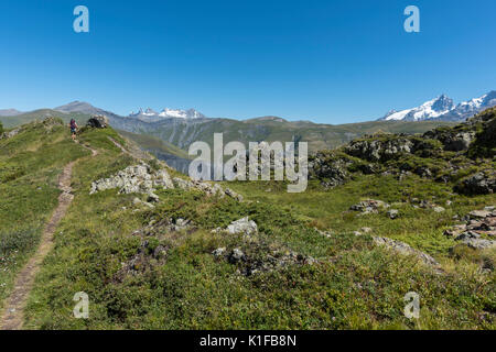 Wanderer Frau zu Fuß auf den Weg in den Französischen Alpen Landschaft mit schneebedeckten Gipfeln im Hintergrund, Kalte de Sarenne, Isère, Oisans, Frankreich Stockfoto