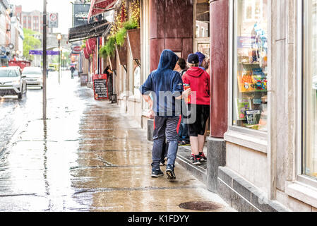 Quebec City, Kanada - 31. Mai 2017: Altstadt Straße Saint-Jean bei starkem Regen mit Tropfen und Menschen auf der Suche nach Unterschlupf Stockfoto