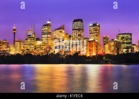 Stadt Sydney CBD hoch aufragenden Türmen oben Royal Botanic Gardens bei Sonnenuntergang reflektieren helle Beleuchtung im Wasser des Hafens von Sydney. Stockfoto