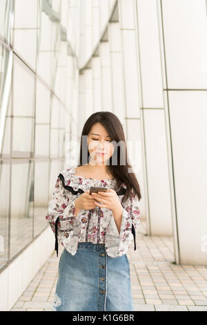 Schöne junge asiatische Mädchen in der Bibliothek verwenden, Tel. Stockfoto