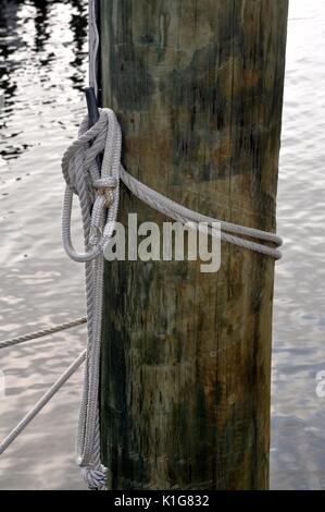Weiße nautische Seil um einen Pylon mit Wasser im Hintergrund gebunden Stockfoto