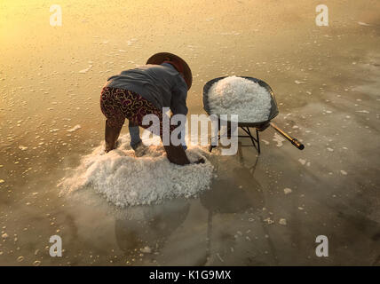 Eine Frau Salz Ernte bei Sonnenaufgang in Ninh Hoa, Vietnam. Ninh Hoa gilt als eines der größten Salz Felder im ganzen Land. Stockfoto