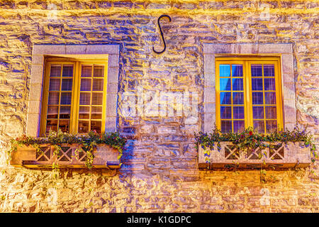 Farbenfrohe Gebäude aus Stein windows auf der Straße während der Dämmerung in europäischen Stadt mit blumenbeet Kisten auf Fensterbänken Stockfoto