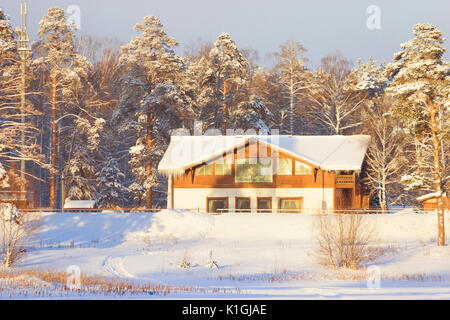 Bild von einem Chalet befindet sich in einem Wald mit Schnee bedeckt. Stockfoto