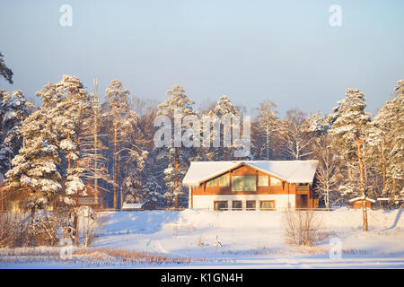 Bild von einem Chalet befindet sich in einem Wald mit Schnee bedeckt. Stockfoto
