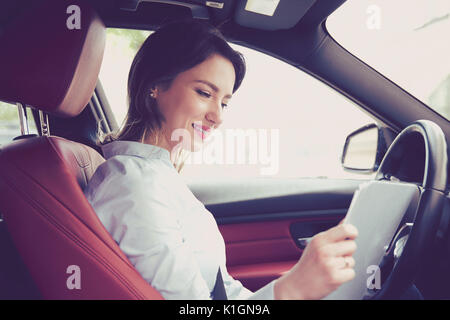 Transport und Ownership Konzept. Junge attraktive Frau im neuen Auto lesen Signatur von Dokumenten Stockfoto