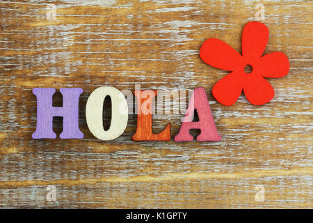Hola (das heißt hallo in Spanisch) mit bunten Holz- buchstaben und rote Blume geschrieben Stockfoto