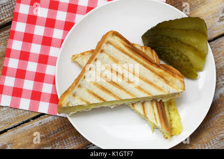 Zwei Stücke von Toast mit geschmolzenem Käse mit Gurke auf der Seite Stockfoto