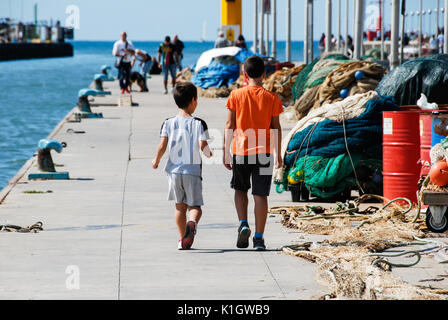 Zwei Kinder Spaziergang auf dem Dock unter den Fischernetze an einem sonnigen Tag. Stockfoto