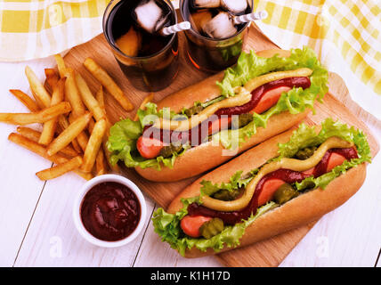 Hot Dogs, Kartoffelecken und Cola auf Holzbrett, Ansicht von oben. Fast food. Stockfoto