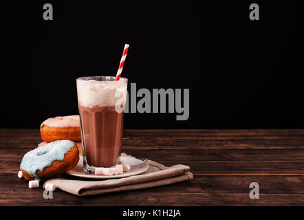 Milchshake mit Donuts und andere Süßigkeiten auf einem dunklen Hintergrund mit Platz für Text Stockfoto