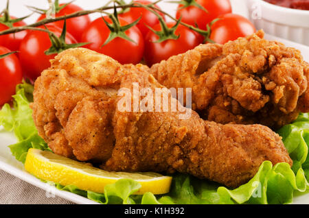 Chicken Drumsticks paniert mit Tomaten und Salat close-up Stockfoto