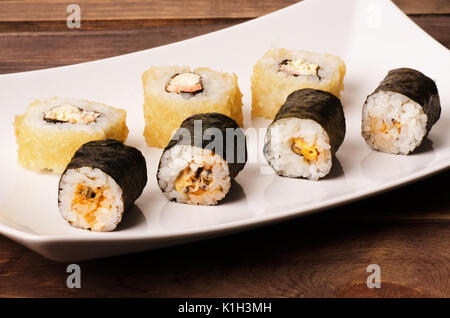 Sushi Rollen in einem weißen Teller auf einem Holztisch Stockfoto