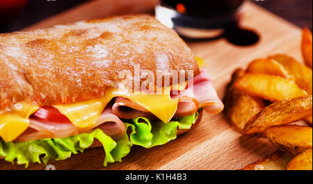 Sandwich mit Schinken, Käse, Tomaten, Salat und Potato Wedges fried Close-up auf Tisch im Restaurant Stockfoto