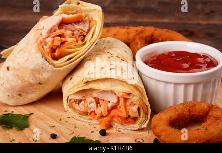 Shaurma mit Huhn mit panierte Zwiebeln auf einem Holzbrett. Bier Snack. Stockfoto