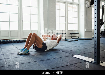 Ältere Menschen in Sportkleidung, Sit Ups allein während der Arbeit aus auf dem Boden einer Turnhalle Stockfoto