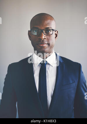 Porträt einer selbstbewussten jungen afrikanischen Geschäftsmann in Anzug und Brille allein in einem Büro Stockfoto