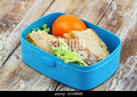 Rustikales Brot Sandwiches mit Käse und Salat in Lunch Box und Mandarine auf Holz- Oberfläche Stockfoto
