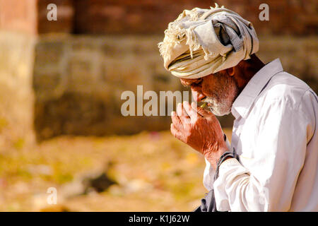 Eine alte indische Mann ist Rauchen beedi (ein indischer Zigarre) in seiner Freizeit. Stockfoto