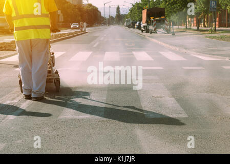 Arbeitnehmer ist Malen zebra Fußgängerzone crosswalk Linien auf dem Asphalt Oberfläche Stockfoto