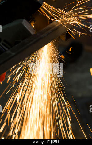 Funken sind aus einer Schleifscheibe während ein Mitarbeiter schneiden ein Stahlrohr. Stockfoto