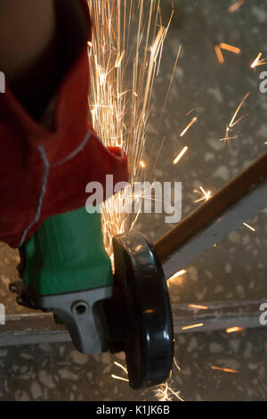 Funken sind aus einer Schleifscheibe während ein Mitarbeiter schneiden ein Stahlrohr. Stockfoto