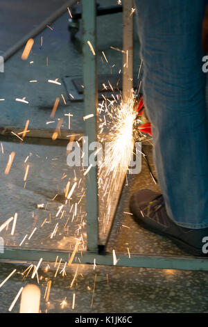 Funken sind aus einer Schleifscheibe während ein Mitarbeiter schneiden ein Stahlrohr. Stockfoto