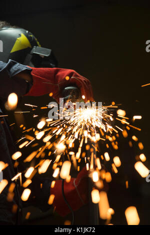 Funken sind aus einer Schleifscheibe während ein Mitarbeiter schneiden ein Stahlrohr. Stockfoto