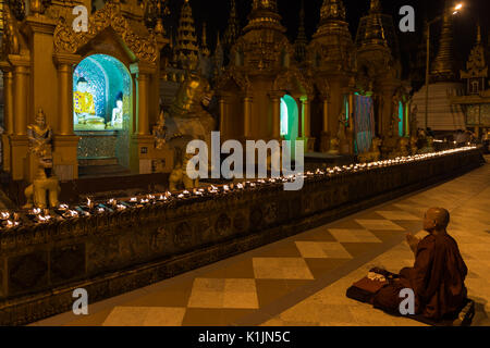 Buddhistischer Mönch betet vor Buddha Bild in der Shwedagon Pagode, Yangon, Myanmar. Stockfoto