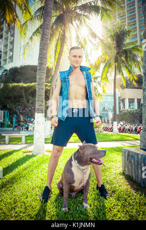 Mensch und Hund American Pit Bull Terrier Relaxen im Park bei Sonnenuntergang Stockfoto