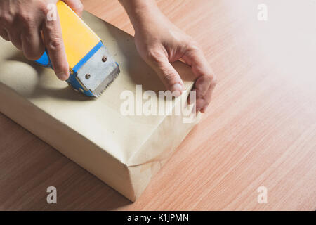 Männliche Abdichtung mit Klebeband kleine Box für bewegte. bis in der Nähe der Hände der männlichen Holding Verpackungsmaschine und Verschließen von Kartons. Stockfoto